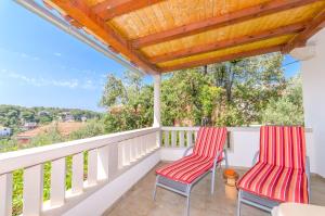 two red chairs sitting on the balcony of a house at House Anima in Maslinica