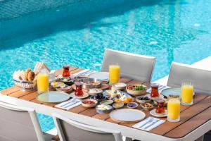 a table with breakfast food and drinks next to a pool at Muse Alaçatı in Alacati