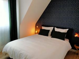 a bedroom with a white bed with a black headboard at Chez Catherine et Laurent in Ploemeur