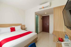 a bedroom with a large bed and a television at Villa Kampoeng City Pacet Mitra RedDoorz in Mojokerto