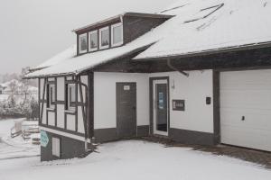 une maison avec un garage dans la neige dans l'établissement WohnZauber, à Winterberg