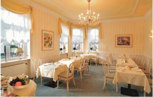 uma sala de jantar com mesas e cadeiras e um lustre em Hotel Residenz Joop em Magdeburg