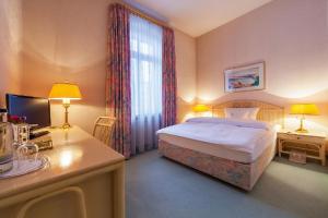 a hotel room with a bed and a desk with a computer at Hotel Residenz Joop in Magdeburg