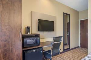 a hotel room with a desk with a tv and a chair at Sleep Inn & Suites Steubenville at the University in Steubenville