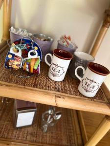 una estantería de madera con tres tazas de café. en Il gufo e il gatto del lago, en Travedona