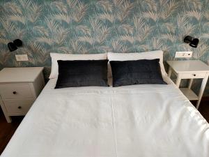 1 cama con sábanas blancas y almohadas negras en un dormitorio en Pensión Boutique AdMera Cerca hospital Clínico en Santiago de Compostela