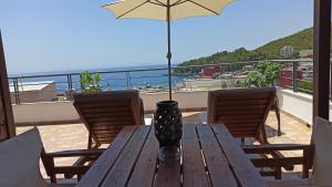 a wooden table with two chairs and an umbrella on a balcony at Bourbos Summer Rooms in Himare