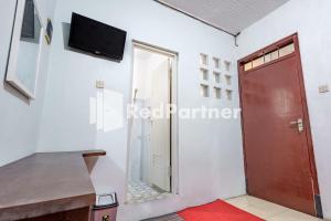 a room with a door and a tv on the wall at Nafisa Homestay Syariah Near Jatim Park 3 Batu Mitra RedDoorz in Malang