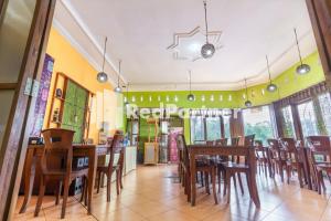 a dining room with wooden tables and chairs at Nafisa Homestay Syariah Near Jatim Park 3 Batu Mitra RedDoorz in Malang