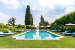 uma grande piscina com cadeiras e guarda-sóis em Byblos Art Hotel Villa Amistà em San Pietro in Cariano