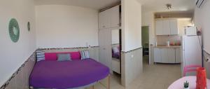 a purple bed in a room with a kitchen at Beau 2 pièces et Beau studio clair en plein centre ville Netanya in Netanya