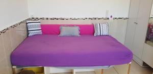 - un lit violet avec des oreillers au-dessus dans l'établissement Beau 2 pièces et Beau studio clair en plein centre ville Netanya, à Netanya