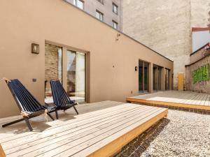 duas cadeiras sentadas num deque de madeira em frente a um edifício em numa l Wood Rooms & Apartments em Viena