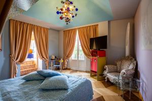 a bedroom with a bed and a chair and a chandelier at Byblos Art Hotel Villa Amistà in San Pietro in Cariano