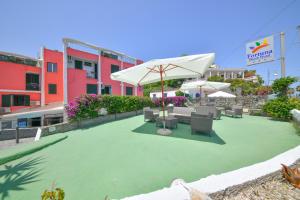 een patio met stoelen en een parasol op een gazon bij Fortuna Beach - Seaside Hotel in Ischia
