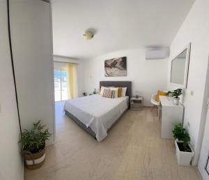 a white bedroom with a bed and a window at Noufaro rooftop-sea view apartment in Zipárion