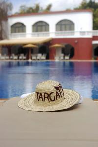 a hat sitting on a table in front of a pool at Targafit Hotel & Hammam in Marrakesh