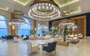 a lobby with tables and chairs and chandeliers at Royal Tulip Korbous Bay Thalasso & Springs in Qurbuş