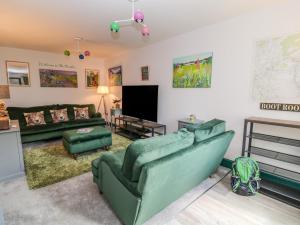 a living room with two green couches and a tv at Herdwick Cottage in Brampton