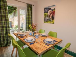 a dining room with a wooden table and green chairs at Herdwick Cottage in Brampton