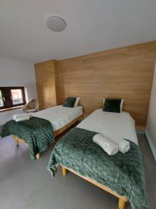 - une chambre avec 2 lits avec des draps verts et blancs dans l'établissement Thon chez toi, à Andenne
