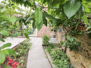 a garden with a brick wall and a sidewalk at Postman's Cottage in Bridlington
