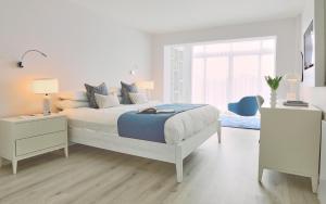 a white bedroom with a bed and two night stands at St Moritz Hotel and Cowshed Spa in Polzeath