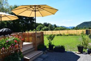 a wooden bench with an umbrella and a fence at Luxus Ferien-Lodge Lurger-Fasching in Rohrbach An Der Gölsen