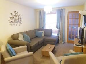 ein Wohnzimmer mit einem Sofa und 2 Stühlen in der Unterkunft Aviemore Glenlivet Lodge in Aviemore