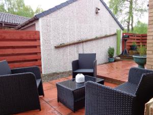 eine Terrasse mit Stühlen, einem Tisch und einem Zaun in der Unterkunft Aviemore Glenlivet Lodge in Aviemore