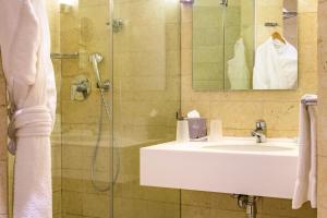 a bathroom with a sink and a shower with a mirror at Grand Tala Bay Resort Aqaba in Aqaba