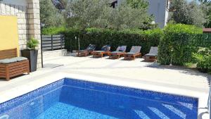 a swimming pool with lounge chairs next to a house at House Yellow in Šilo
