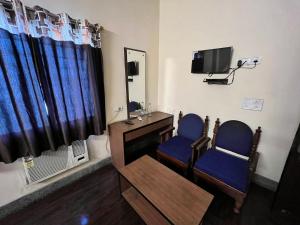 Habitación con 2 sillas, TV y espejo. en Hotel Chandra, en Jamshedpur