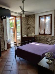 a bedroom with a purple bed and a stone wall at B&B Cagnona in Borghi