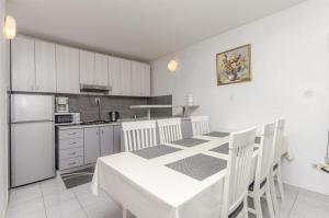 a kitchen with a white table and white cabinets at Apartments Ercegovic in Rogoznica