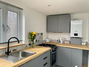 a kitchen with white cabinets and a sink with a vase of flowers at The Little Hideaway in Truro