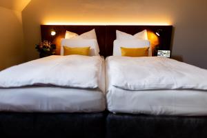 2 letti con cuscini bianchi posti uno accanto all'altro di BC Hotel Bad Kreuznach mit Restaurant Mühlentor a Bad Kreuznach