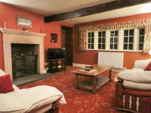 a living room with a fireplace and a table at Hawkyard's Cottage in Oldham