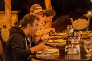 Akagera Transit Lodge في Akagera: مجموعة من الناس يجلسون على طاولة يأكلون الطعام