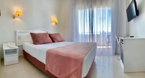 1 dormitorio con 1 cama, TV y ventana en Hotel Aromar en Platja  d'Aro