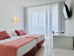 a hotel room with two beds and a television at Hotel Aromar in Platja  d'Aro