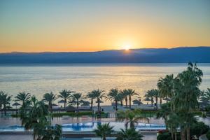 a sunset over the ocean and palm trees at Grand Tala Bay Resort Aqaba in Aqaba