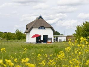a white building with a thatched roof in a field of flowers at Villa Fasan in Trent