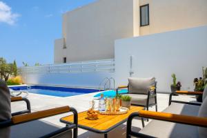 eine Terrasse mit Stühlen, einem Tisch und einem Pool in der Unterkunft Protaras Almaria Villa 16 in Protaras