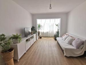 a living room with a white couch and a tv at Apartamentul cu plante Etaj 4 in Mangalia