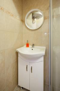La salle de bains est pourvue d'un lavabo blanc et d'un miroir. dans l'établissement Heroes Square & City Park Thermals Apartment, à Budapest