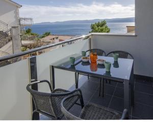 a table and chairs on a balcony with a view of the ocean at Apartments Lorenzo in Lokva Rogoznica