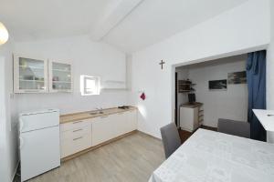 a kitchen with white cabinets and a table and a cross at House Tony in Tkon