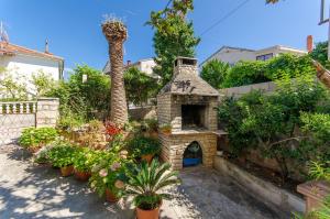 a garden with a stone fireplace and a palm tree at Apartments KATA in Supetar