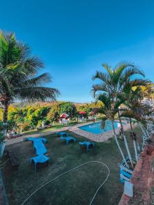 a pool with blue picnic tables and palm trees at Pousada 2 Baioco in Paty do Alferes +34 photos